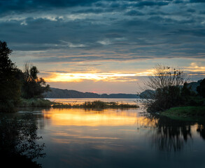 Sunrise idyll landscape on a river with a cloudy sky at golden hour
