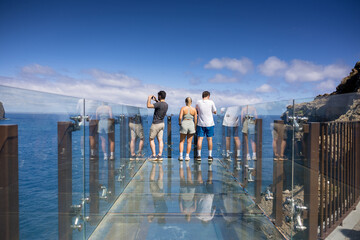 Group of tourists taking photos on Miradouro do Guindaste viewpoint. Madeira island, Portugal