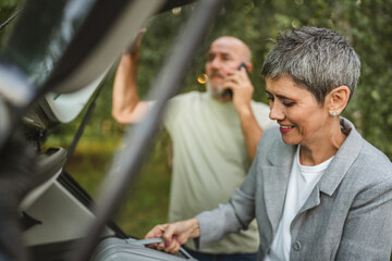 Elderly couple loading car trunk with items before a journey together