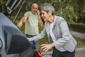 Naklejka premium Elderly couple loading car trunk with items before a journey together