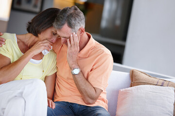 Couple, hug and crying in home with support, grief and bad news with relationship stress. Mature people, sad and depression on living room sofa with compassion, heartbreak and crisis in marriage