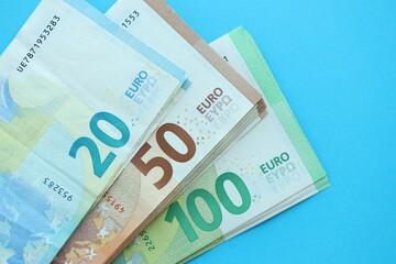Big amount of one hundred, twenty and fifty euro money bills on blue background