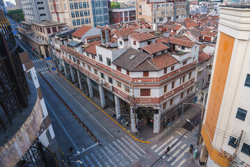 Obraz premium A vibrant street in Shanghai features a traditional building with red tiled roofs amidst modern and older structures, highlighting architectural contrasts.