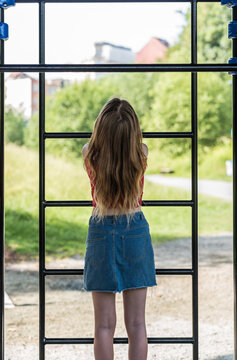Attractive 20 yo woman in short skirt turning her back on a climbing frame, Brussels, Belgium