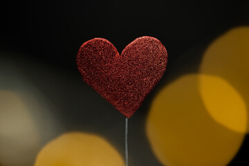 un corazón rojo con fondo negro y bokeh al frente