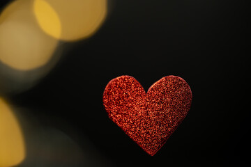un corazón rojo brillante con bokeh y fondo negro