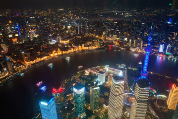 Shanghai's skyline at night features the illuminated Oriental Pearl Tower, with the Huangpu River dividing Pudong's skyscrapers from the historic Bund.