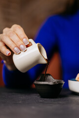 Close-up of a hand pouring soy sauce into a dipping bowl, perfect for sushi or Japanese cuisin