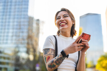 Happy young woman using mobile phone in the city
