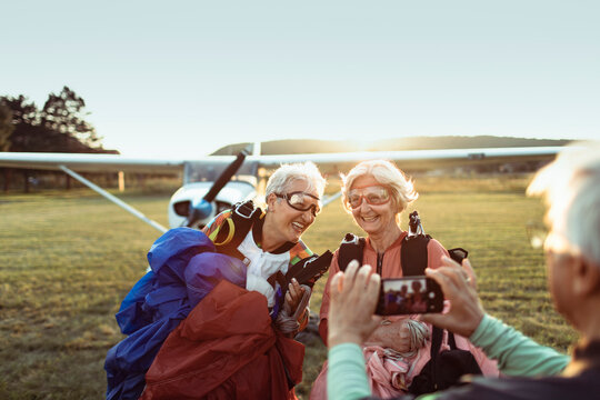 Two senior women laughing after skydiving adventure at sunset