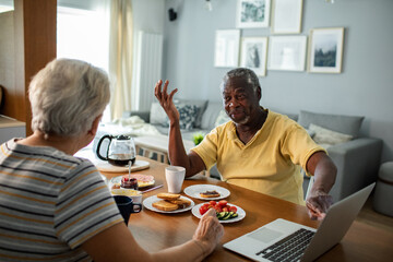Happy senior couple eating breakfast together at kitchen table