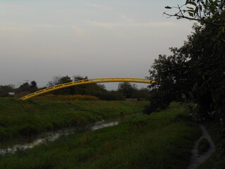 Yellow, arched pipeline over the river.