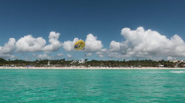 paraca&iacute;das sobre un paisaje playero con un mar de aguas cristalinas color turquesa en el caribe.  