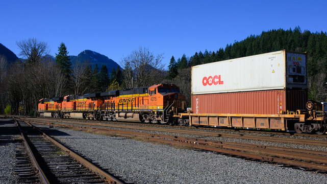 Skykomish, WA, USA - November 6, 2024; BNSF freight train with intermodal cargo under clear blue sky and with track