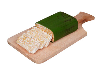 A block of banana-leaf-wrapped raw tempeh and a few slices on a wooden cutting board isolated transparent