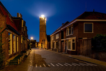 Night cityscape, The Vuurtoren Brandaris with illuminated lighthouse and stars, Houses on the Dutch Wadden Sea, A municipality and an island in the northern, Friesland, West-Terschelling, Netherlands.