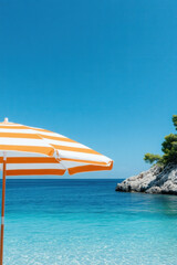 Fototapeta premium Orange umbrella on the tropical beach for vertical background
