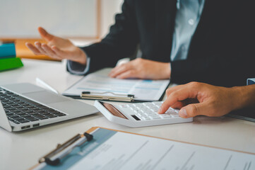 close up The business person is sitting on a calculator with a graph in the office of finance accounting concept