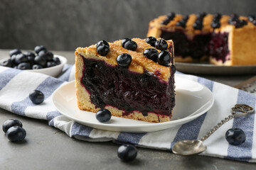 Slice of delicious homemade blueberry pie served on grey table, closeup