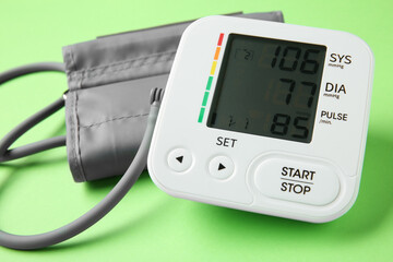 Blood pressure measuring device on green background, closeup