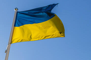 The Ukrainian flag flutters in the wind against the background of the autumn sky