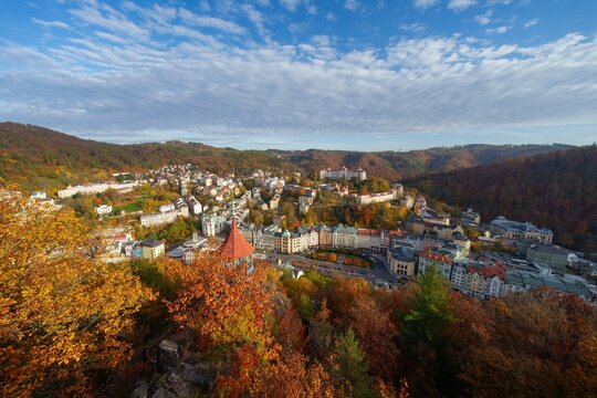 Karlovy Vary city aerial panoramic view in with row of colorful multicolored buildings and spa hotels in historical city centre. Panorama of Karlsbad town and Slavkov Forest mountains in autumn.