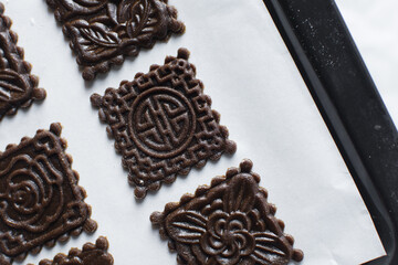 top view of stamped gingerbread cookie dough, Overhead view of cut out molasses cookie dough on a marble countertop, process of making christmas cookies