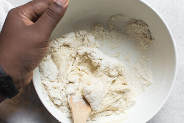Overhead view of challah dough being mixed, top view of homemade challah dough being mixed in a white bowl, process of making challah