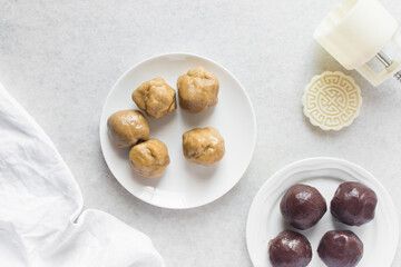 Overhead view of mooncake dough and red bean paste balls in a white plate, top view of mooncake dough and sweet adzuki bean paste balls in a white plate, process of making mooncakes