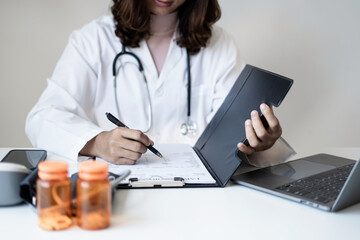 Female doctor holding a medicine bottle is checking the quality of medicine for any side effects the patient or not and recording patient information at the hospital. medical and health care concept