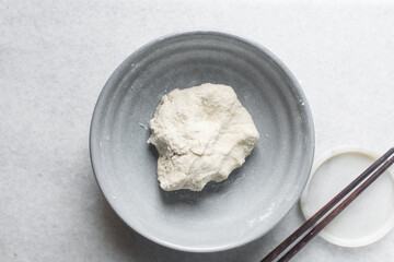 Overhead view of noodles dough in a grey bowl, top view of homemade biang biang noodles, process of making hand pulled noodles