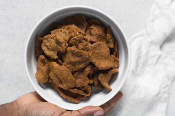 Overhead view of kuli-kuli in a white bowl, top view of nigerian groundnut cakes in a bowl, fresh homemade nigerian kulikuli in a ceramic bowl
