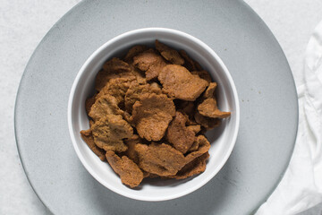 Overhead view of kuli-kuli in a white bowl, top view of nigerian groundnut cakes in a bowl, fresh homemade nigerian kulikuli in a ceramic bowl