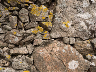Old, rough, natural dry stone wall with lichen background texture.