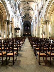 Photo of the interior view of a large cathedral, Swiss, with rows and rows of wooden chairs facing forward for people to sit on