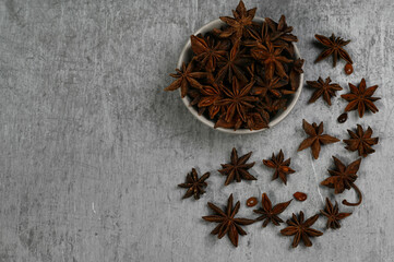 Star anise in a bowl on a grey concrete background with copy space, top view
