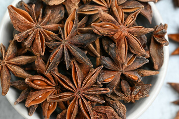 A close-up shot of star anise in a bowl, showcasing its rich brown color and intricate shapes, the photo captured from above