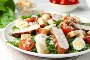 Tasty Caesar salad with chicken and tomatoes on white wooden table, closeup
