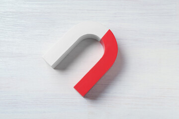 One horseshoe magnet on white wooden background, top view