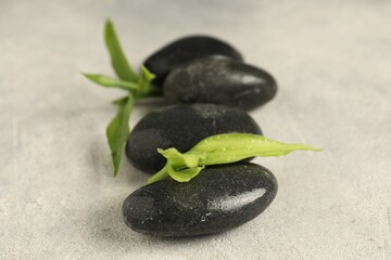Spa stones and green leaves on grey table, closeup