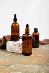 Amber Glass Bottles with Dropper and Screw Cap on Stone Blocks and Fabric Accent