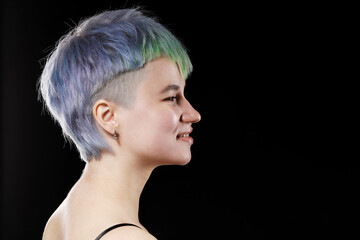 Profile of young woman with stylish short haircut and colored hair dyeing - blue-green hair. Side view.