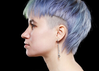 Profile of young woman with stylish short haircut and colored hair dyeing - blue-green hair. Side...