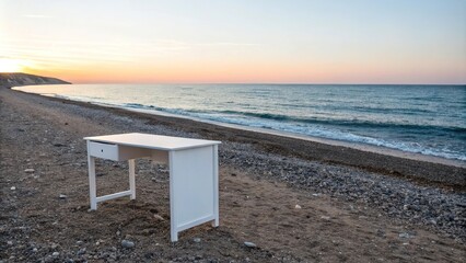 A simple white desk placed on a rocky beach with a distant summer sunset and a clear blue ocean, sky, warm, open space, summer, peaceful