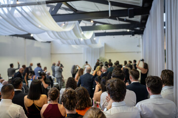 wedding ceremony celebrating marrage, with a wedding party crowd taking photos and videos of the party dancing and watching