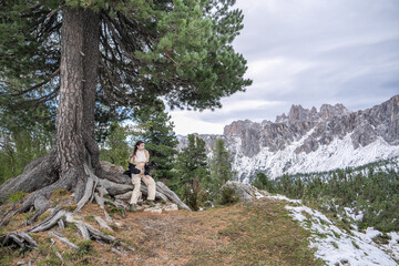 Obraz premium Woman sitting under the tree enjoy the view of alpine mountain landscape snowy.