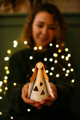 Festive Christmas image of woman hands holding angel figurine. Angel figurine in warm Christmas...