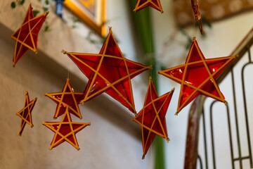 hanging star-shaped decorations with red and yellow frames, arranged in a cozy, softly lit indoor setting. The stars create a festive, whimsical atmosphere against a blurred background.