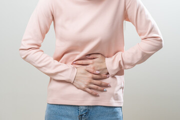 Flatulence asian young woman intolerance hand in stomach ache, suffer from food poisoning, abdominal pain and colon problem, gastritis or diarrhoea when at home. Patient belly, abdomen or inflammation