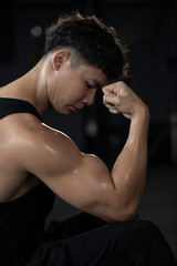 Sportsman or athlete  showing off his arm muscles in the fitness gym. Happy and positive people workout.